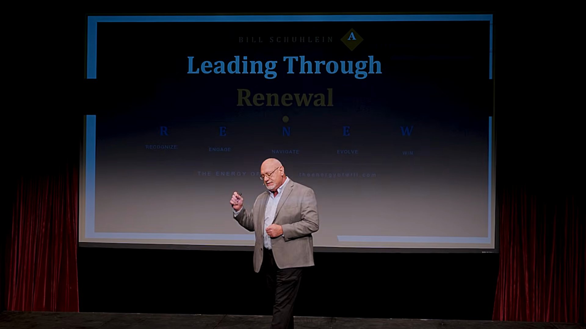 Bill Schuhlein on stage in front of his Leading Through Renewal slide